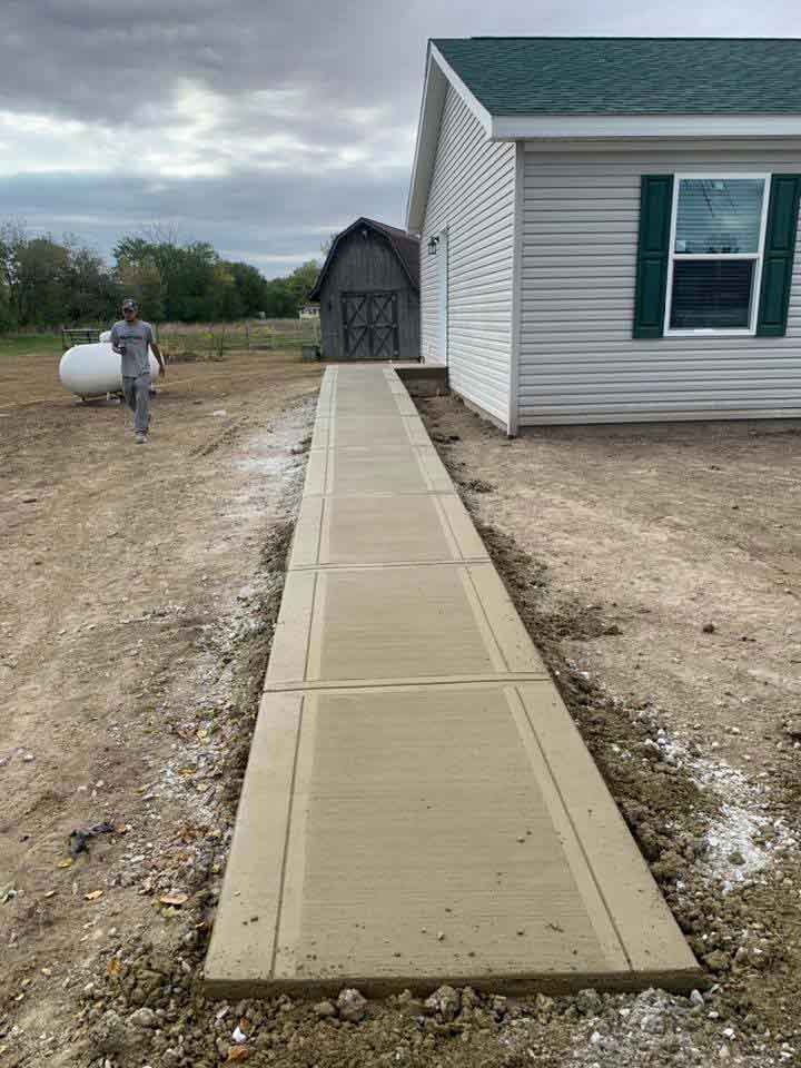 long new concrete sidewalk from the side exit door of a house